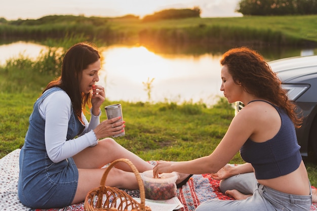 Twee meisjes rijden met de auto over de weg en zijn gestopt voor een picknick langs de weg