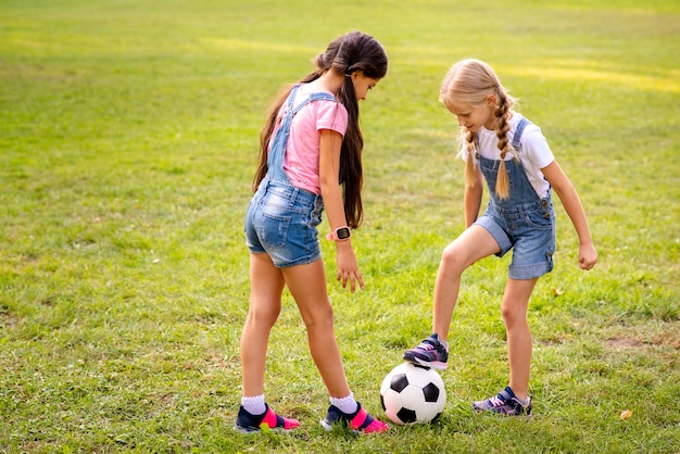 Foto twee meisjes spelen met voetbal op gras