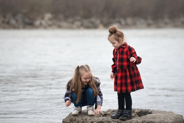 Twee meisjes van verschillende leeftijden hebben plezier met spelen in de buurt van het water in de rivier