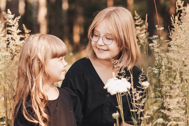 Foto twee meisjes zussen knuffelen in de natuur in de zomer