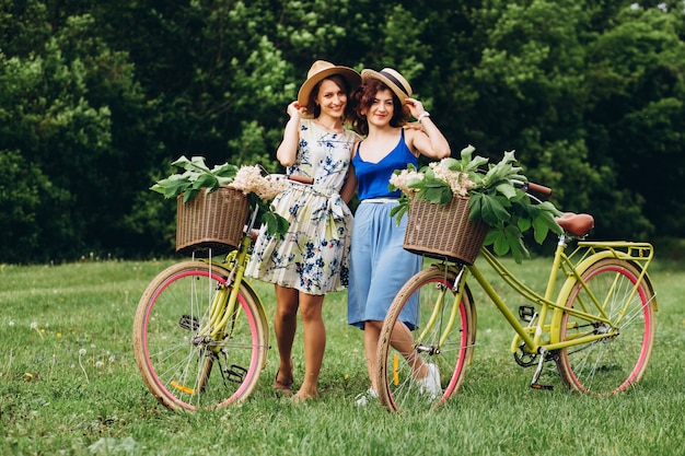 Twee meisjesvrienden met retro fietsen ontspannen in de natuur