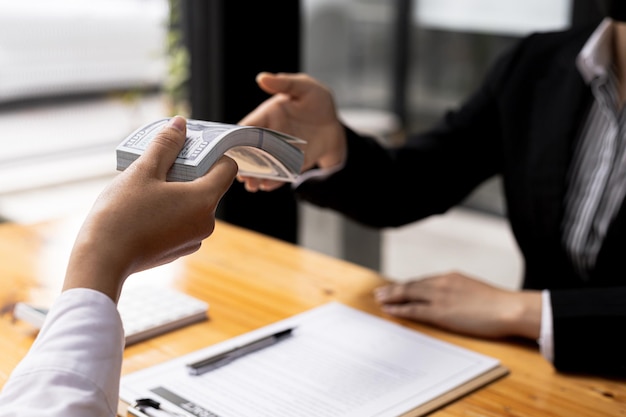 Twee mensen geven elkaar dollarbiljetten, ze zijn zakenpartners die voor beide partijen voordelig zijn, ze plegen omkopingsfraude voor zakelijke belangen. het concept van corruptie en omkoping.