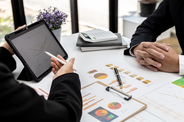 Twee mensen kijken naar het tabletscherm met het financiële overzicht van het bedrijf, zakenmensen brainstormen over ideeën om verliezen op te lossen en plannen strategieën om het bedrijf winstgevend te maken en te laten groeien.