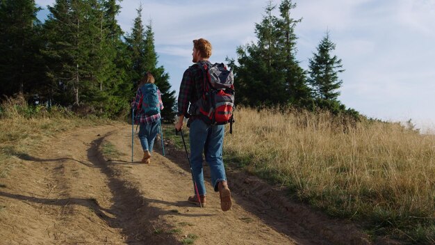 Foto twee mensen lopen over een onverharde weg met bomen op de achtergrond