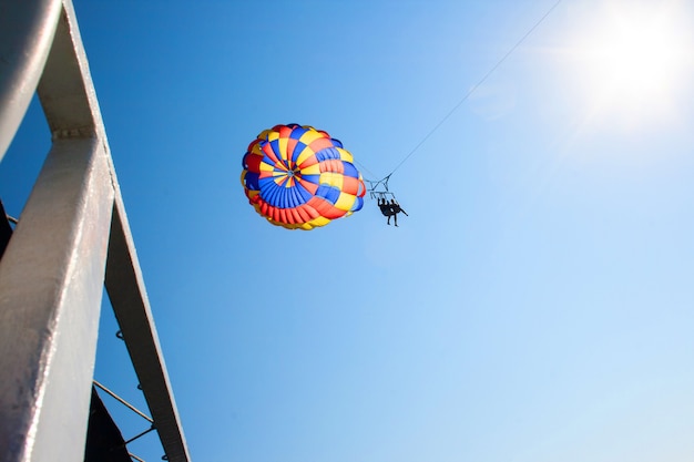 Twee mensen parachutespringen vanaf de betonnen pier boven de zee in de blauwe lucht