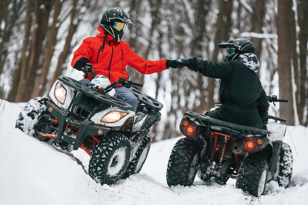 Twee mensen rijden op een ATV in het winterbos.