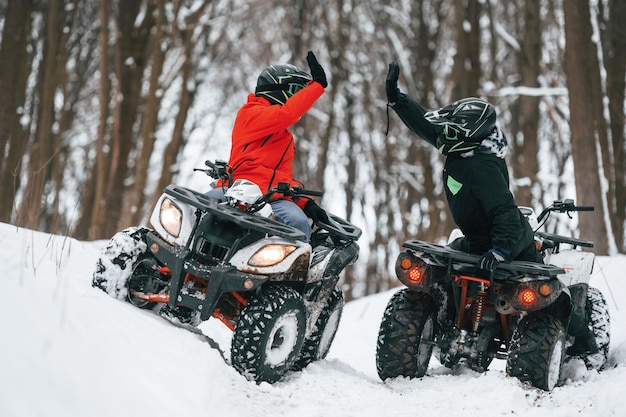 Twee mensen rijden op een ATV in het winterbos.