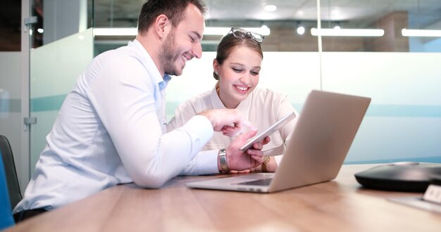 twee mensen uit het bedrijfsleven met behulp van laptop voorbereiding voor de volgende vergadering en het bespreken van ideeën