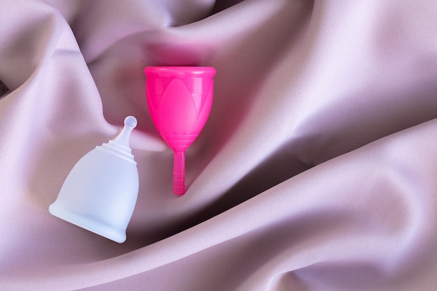 Twee menstruatiecups op zijde roze stof