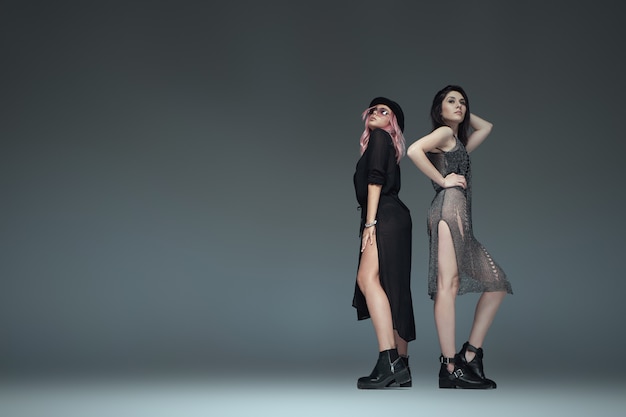 Twee modieuze meisjes dragen zwarte trendy outfits poseren