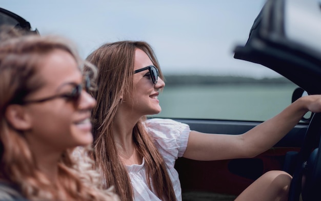 Twee modieuze meisjes reizen in een cabriolet