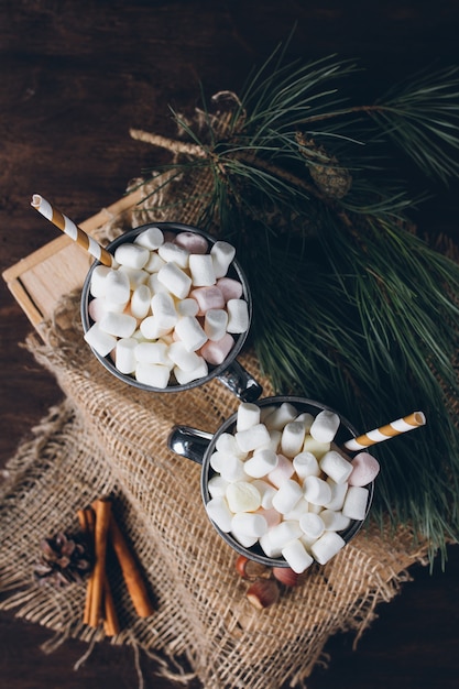 Twee mokken met cacao en marshmallows op een bruine achtergrond