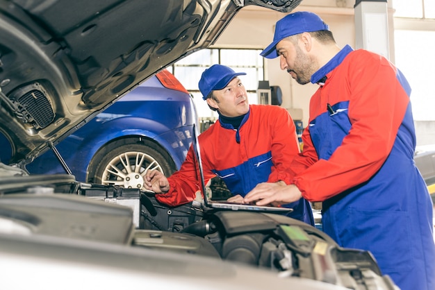 Twee monteurs die werken aan een motor van een auto