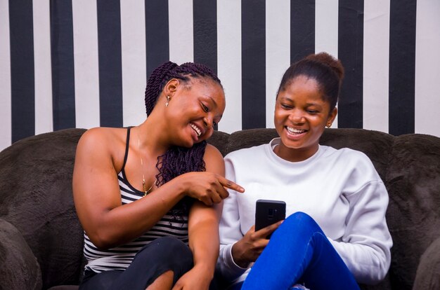 Twee mooie Afrikaanse dames die opgewonden waren over wat ze op hun telefoon zagen