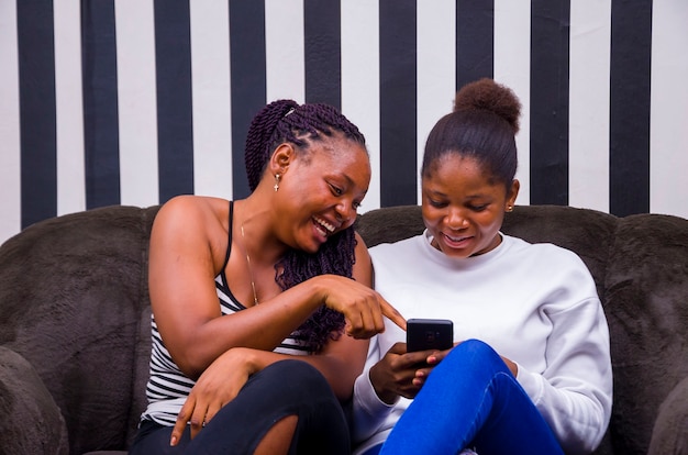 Twee mooie Afrikaanse dames die opgewonden waren over wat ze op hun telefoon zagen