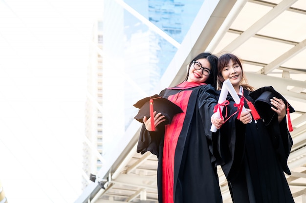 Twee mooie Aziatische meisjes omhelzen de graduatieceremonie