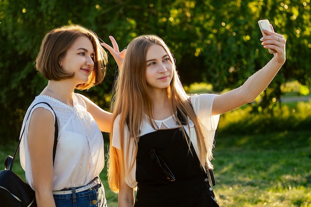 Twee mooie beste vriendinnen schoolmeisjes (student) doen selfie aan de telefoon in het park