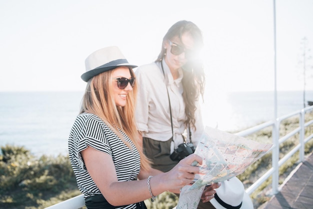 Twee mooie blonde en brunette vrouwen met toeristische kaart op vakantie. Vakantie en toerisme concept