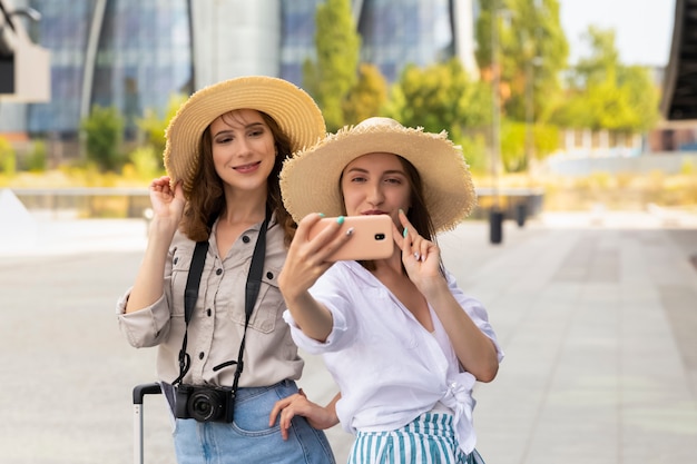 Twee mooie en gelukkige vrouwelijke toeristische meisjes nemen een selfie op het treinstation.