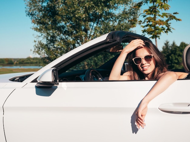 Twee mooie en glimlachende jonge vrouwen in een cabriolet, positieve modellen die buiten rijden.