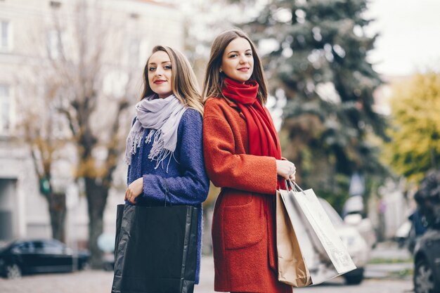 twee mooie en stijlvolle vriendinnen die door de stad lopen met pakjes en boodschappen