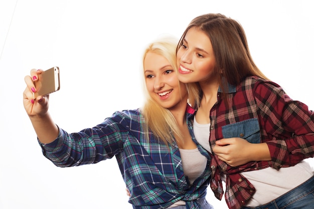 Twee mooie hipstermeisjes die selfie nemen. Geïsoleerd op een witte achtergrond.