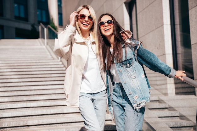 Twee mooie jonge glimlachende vrouwen in trendy zomerkleding buiten vrolijk en gelukkig