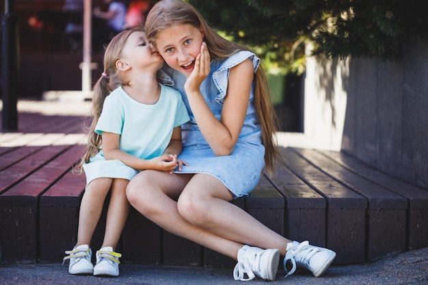 Twee mooie jonge meisjes zitten op de veranda en zijn geheim