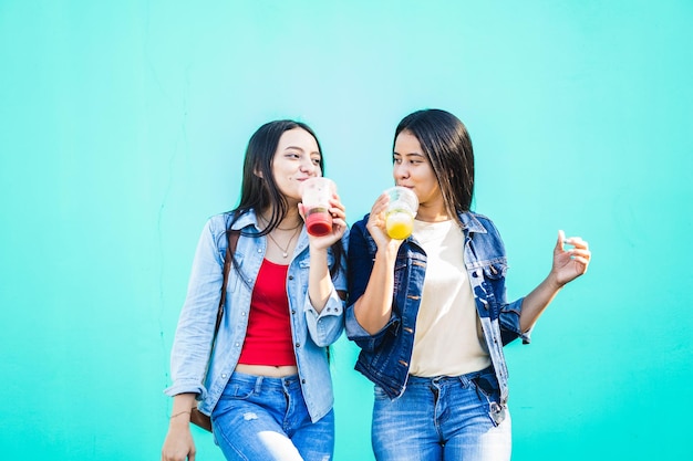 Twee mooie jonge spaanse vrouwen die een sap gezonde levensstijl drinken