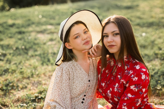 twee mooie jonge vriendinnen in het zomerpark op het gras