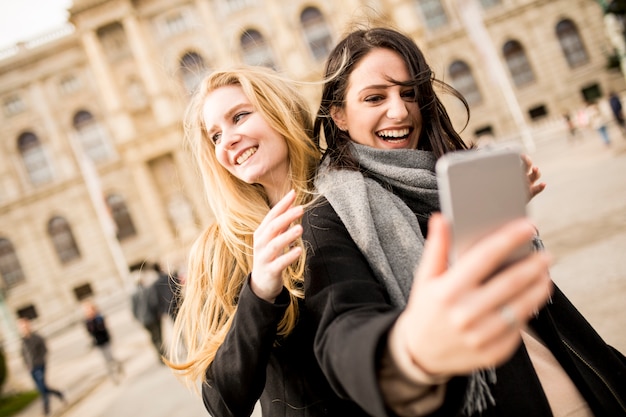 Twee mooie jonge vrouwen die selfie in de stad maken