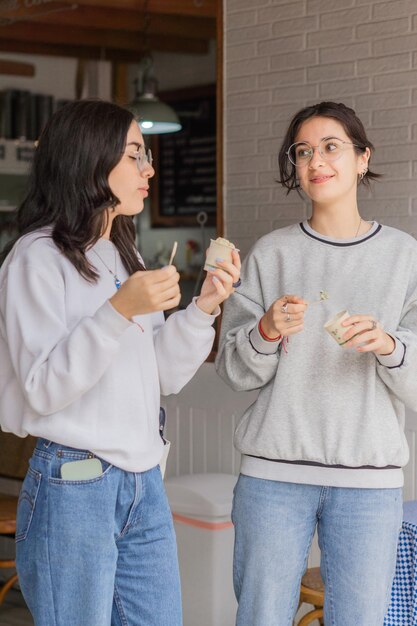 Twee mooie jonge vrouwen lopen en eten ijs.