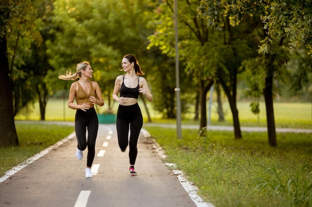 Twee mooie jonge vrouwen rennen op een baan in het park