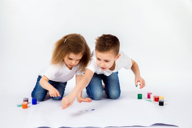 Twee mooie jongen en meisje van kindvrienden tekenen foto's met verf