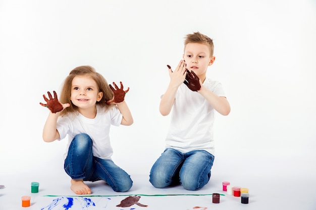 Twee mooie jongen en meisje van kindvrienden tekenen foto's met verf