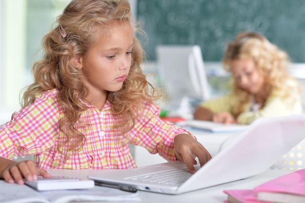 Twee mooie kleine meisjes in de klas met laptop