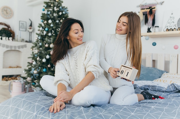 Twee mooie meisjes die een decoratieve houten kalender houden.