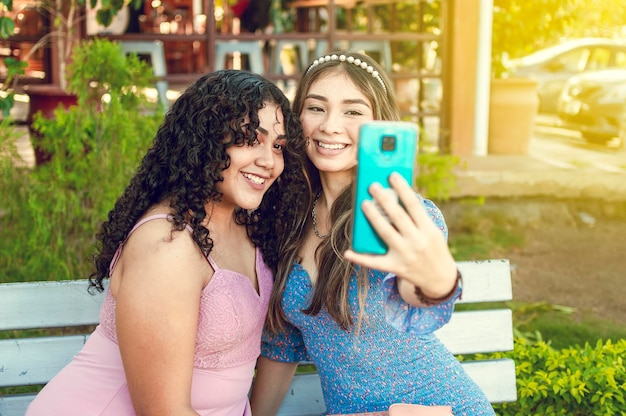 Twee mooie meisjes die op een bank zitten en een selfie nemen, meisjes glimlachen en een selfie maken met zusterlijk vriendschapsconcept