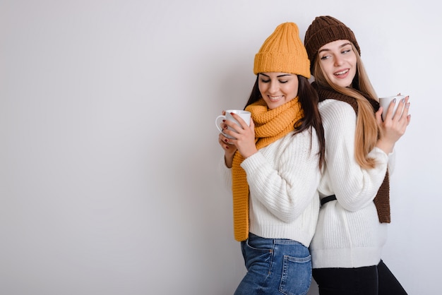 Twee mooie meisjes die warme sweaters op wit dragen