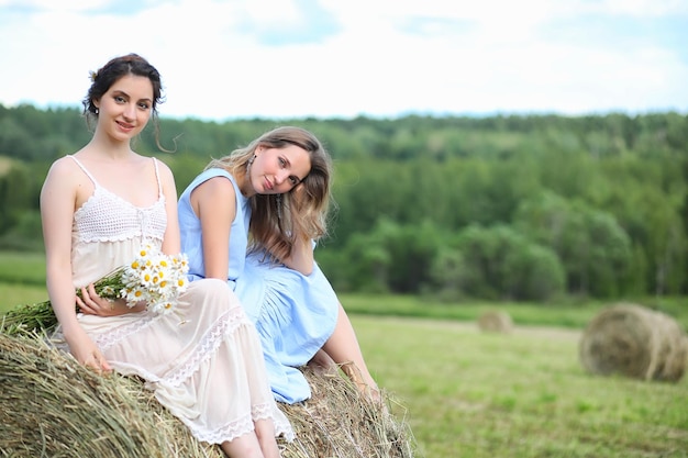 Twee mooie meisjes in jurken in zomerveld met bessen