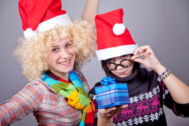 Foto twee mooie meisjes met geschenken in kerstmutsen. studio opname.