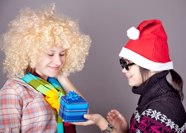 Twee mooie meisjes met geschenken in kerstmutsen. Studio opname.