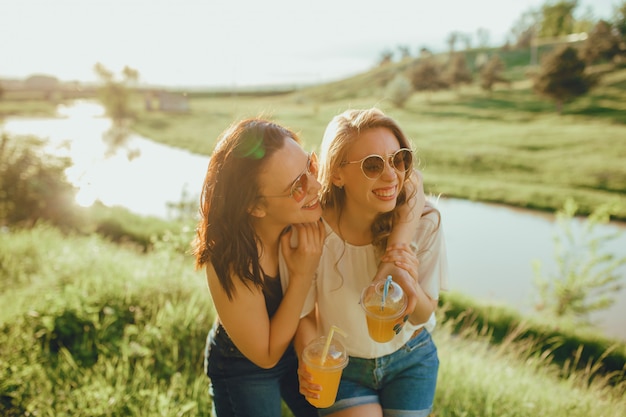 Twee mooie meisjes plezier zomer drinken cocktails, bij zonsondergang, positieve gezichtsuitdrukking, buiten