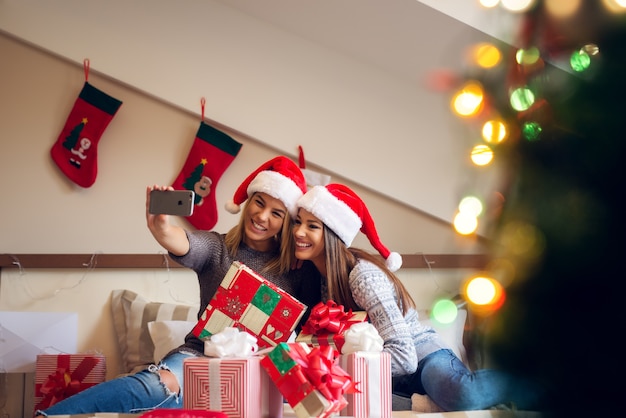 Twee mooie meisjes zittend op bed met een stel cadeautjes voor hen.