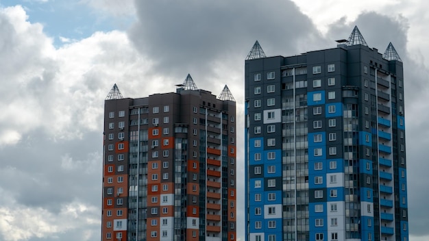 Twee mooie moderne gebouwen met meerdere verdiepingen op de achtergrond van grijze regenachtige wolken Stedelijk landschap Residentiële ontwikkeling