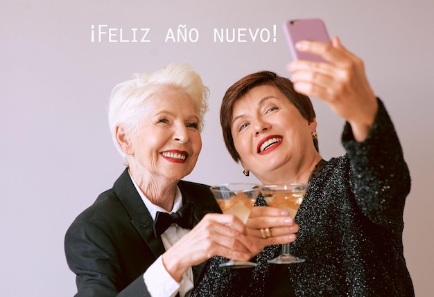 Twee mooie stijlvolle volwassen senior vrouwen die wijn drinken en selfie-foto maken Leuke feesttechnologie