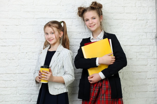 Twee mooie tienermeisjes die boeken vasthouden en glimlachen