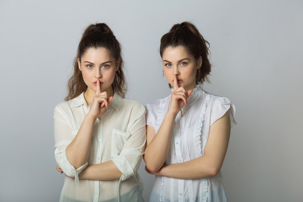 twee mooie tweelingvrouwen met handgebaar