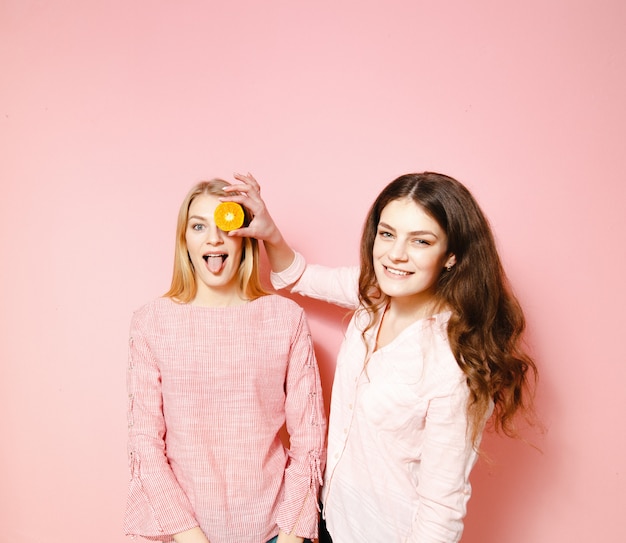 Twee mooie vriendinnen plezier op roze achtergrond.
