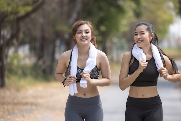 Twee mooie vrouwelijke joggers, vriendinnen die zich uitstrekt in park